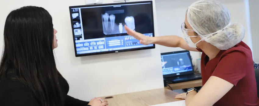 Dentista mostrando exame de imagem à paciente